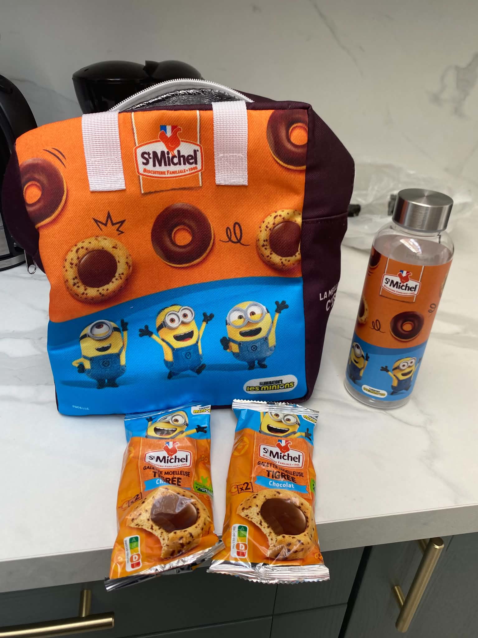 Les Minions comprenant un (1) sac goûter enfant + une (1)  gourde + 120g de produits St-Michel, d’une valeur de 31€ TTC